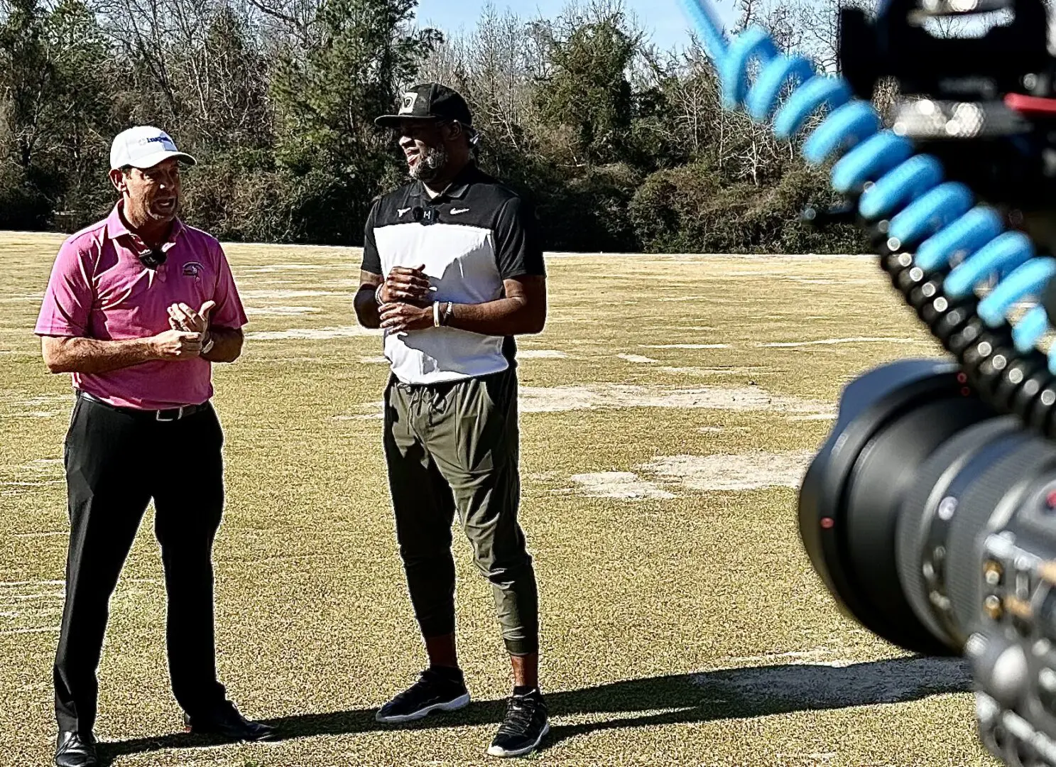 Two men standing in a field with a camera.