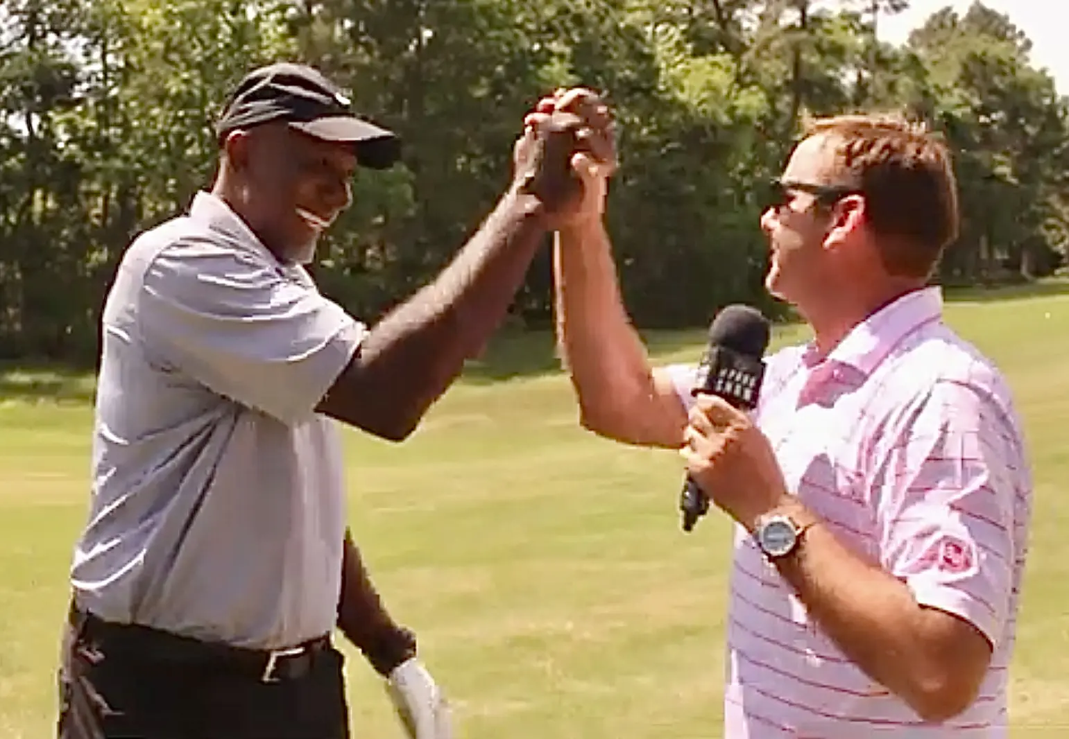 Two men giving each other a high five while holding microphones.