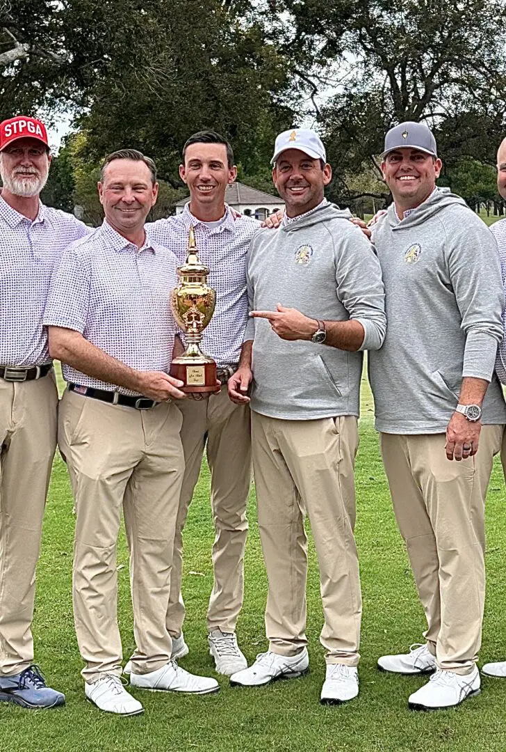 A group of men holding a trophy on top of a field.