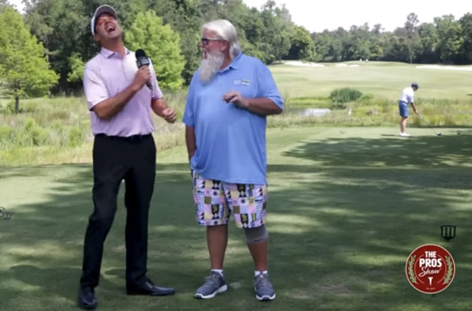 Two men standing on a golf course talking to each other.