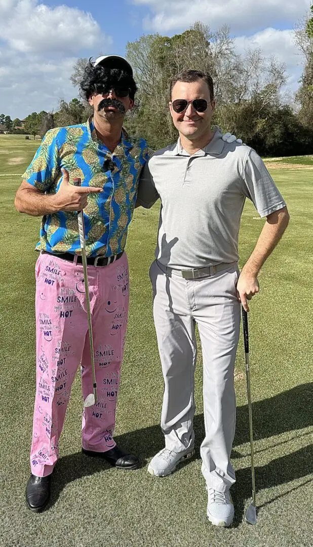 Two men standing on a golf course with their hands in each other 's pockets.